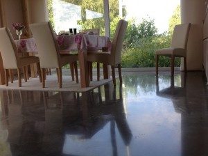 Originalfoto eines reflektierenden mineralischen Bodens im Wohnbereich mit Tisch und Stühlen aus dem vorhandenen Bildbestand