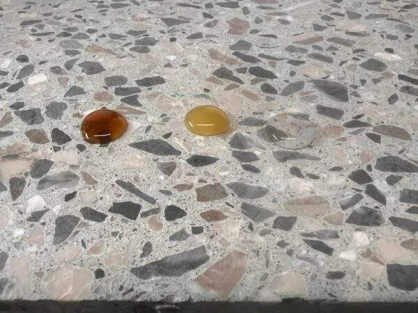 Bestandsfoto: Flüssigkeitstropfen auf einer größeren Terrazzo-Probe mit sichtbarer Gesteinskörnung
